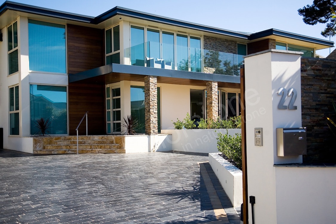 Street View of a Modern Designed Home featuring lots of glass, steel, and stone on its exterior surfaces